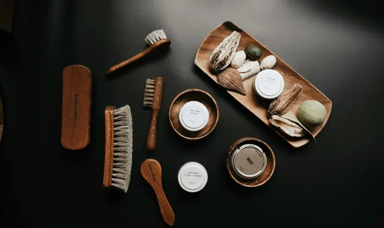 Brushes, polish tins and leather-care tools arranged on a dark surface