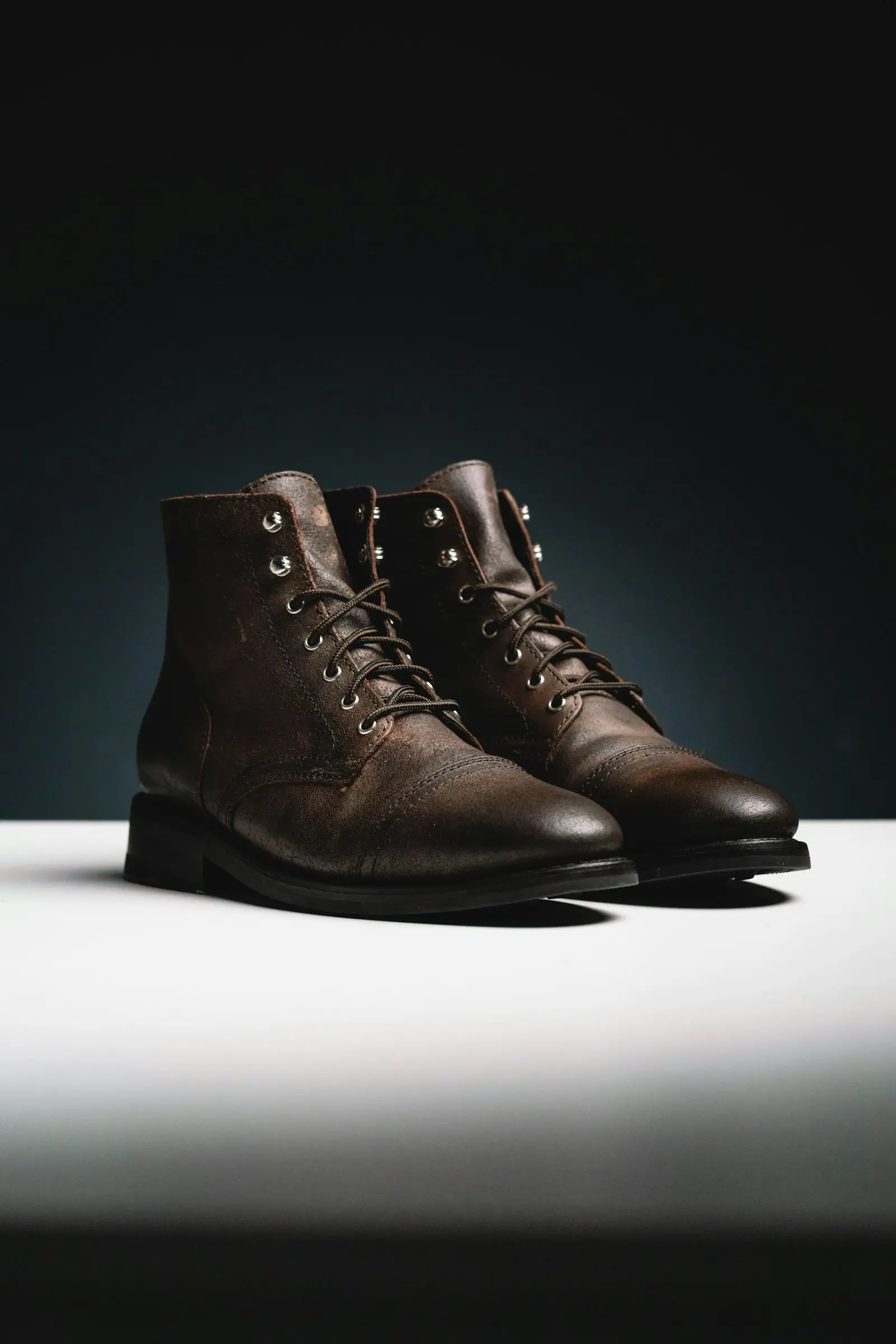 A pair of brown leather lace-up boots on a white surface