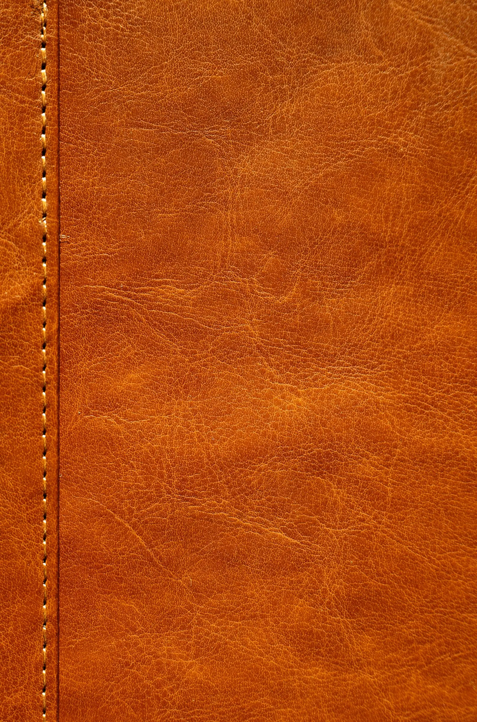 Brown leather surface beside a stitched seam