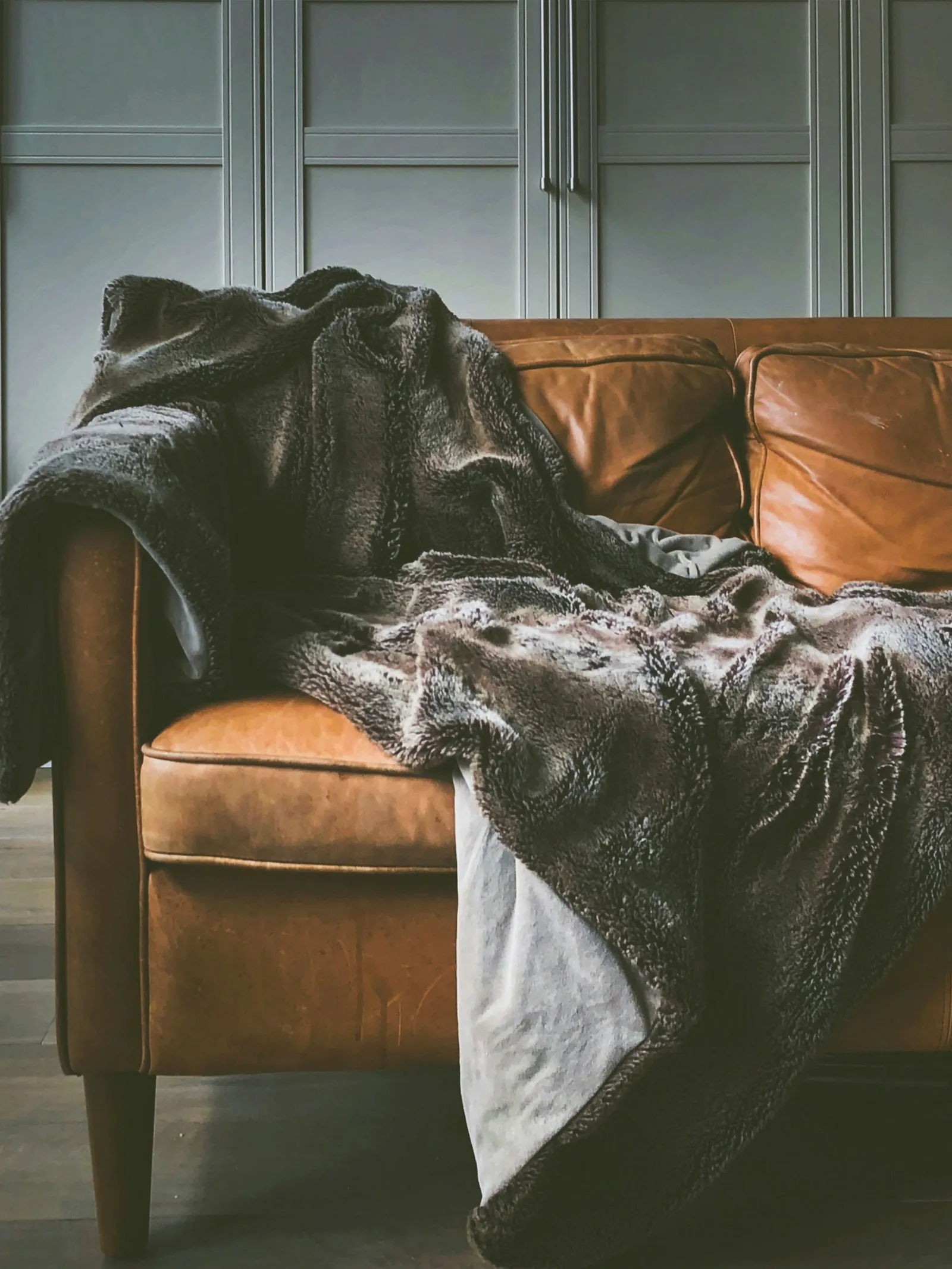A brown leather sofa with a blanket in a room
