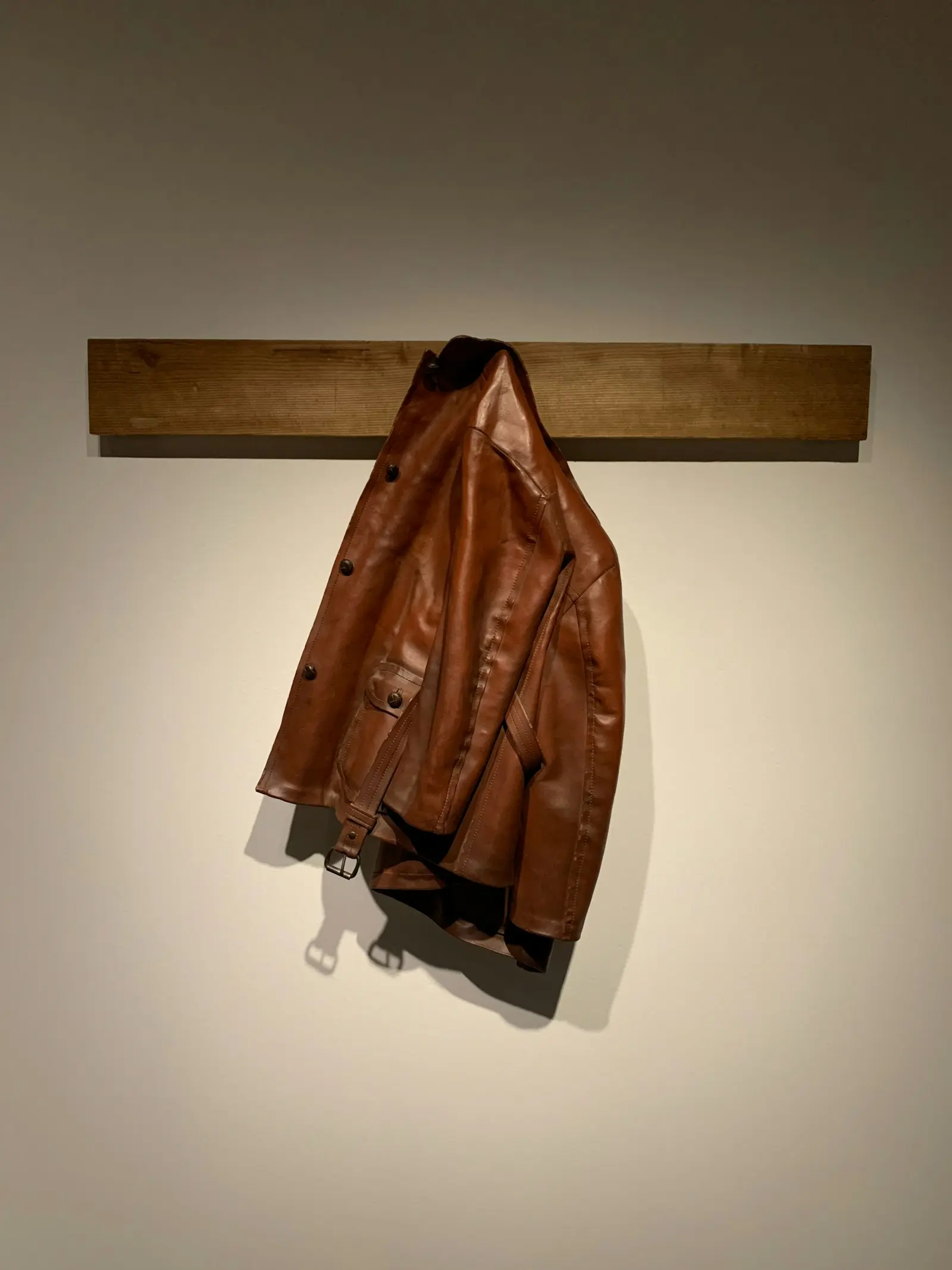 A brown leather jacket hanging against a wall